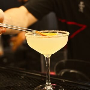 a person is holding a spoon over a martini