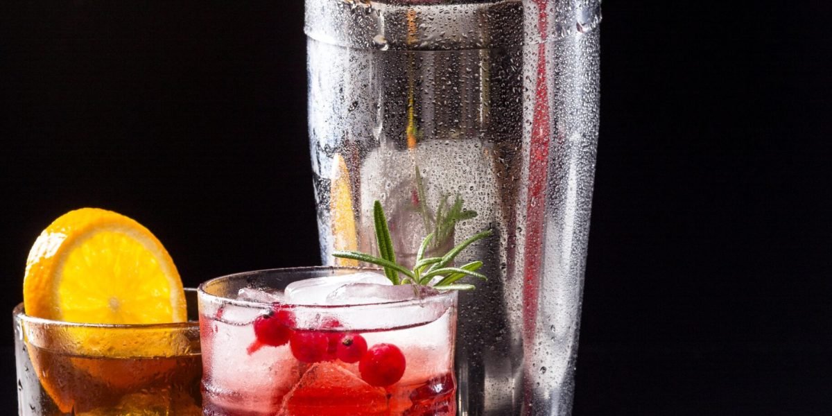 vista-frontal-de-arandano-vodka-y-whisky-con-vasos-de-naranja